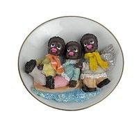 Plate front view showing the detailed raised 3D design of three African American children with colorful scarves and boots, sitting on a sled over blue textured base, set on white plate with gold rim.