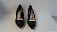 Front view of the black patent leather women's high-heeled shoes size 7.5 showing pointed toes and interior tag with brand.