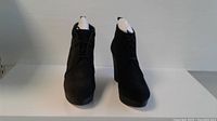 Front view of the black suede wedge boots with lace-up design, showing overall shape and condition.
