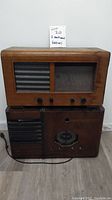 Full view of both antique tube radios stacked, showing wooden cabinets, knobs, and speaker grills