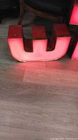 Photo showing single red neon letter 'E' lit up on the floor