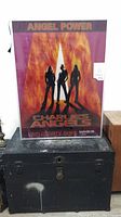 Fluorescent light box featuring Charlie's Angels themed translucent advertising slide with silhouetted figures against flames.
