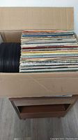 Box filled with multiple LP vinyl records in cardboard sleeves.