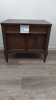 Front view of the wooden nightstand with single drawer and double doors, showing overall structure and condition.