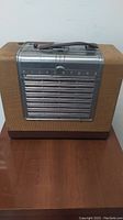 Front view of the Silvertone tube radio showing the fabric cabinet and metal grille front with handle on top.