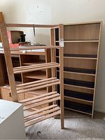 Two wooden shelf units shown standing upright, one with open slatted shelves, the other with solid shelved unit and dark interior.