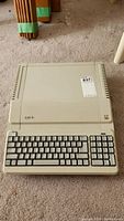 Front view of beige Apple IIe with integrated keyboard lying on carpet.