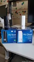 Western Digital My Book and My Cloud 2TB storage devices displayed on a desk with their retail boxes.
