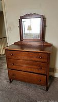 Front view of vintage wooden dresser with mirror showing three drawers and round wooden knobs.