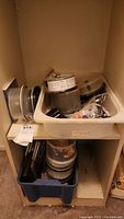 Photo of shelves holding multiple spindle containers of blank CDs and DVDs, with additional items in a plastic bin below.