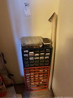 View of tall plastic storage organizer with black and orange drawers and clear plastic boxes stacked on top.
