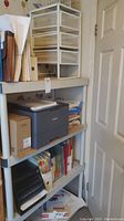 Large plastic shelving unit holding various office supplies and a printer, positioned next to a door.