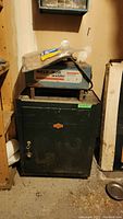 Weld-Mor welder unit placed on top of Eaton Tecomaster metal cabinet with key attached, cabinet shows visible wear and lockable door.