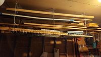 Photo shows assorted wood off cuts and plywood stored on ceiling-hung metal racks.