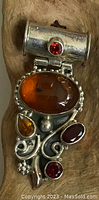Front close-up of silver and amber pendant showing detailed design and multiple stones