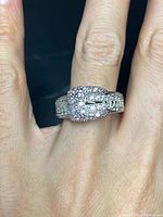 Close-up photo of a sterling silver buckle-shaped ring with clear crystals, worn on a hand. Ring features pave crystal setting and marked 925 for sterling silver.