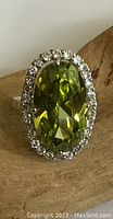 Close-up front of the oval green gem ring with surrounding clear crystals on sterling silver mount.