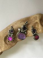 Front view of sterling silver pendant and matching earrings showing purple and pink gem stones and silver bead accents on driftwood display.