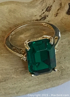 Close-up of the large emerald-cut green gemstone set in sterling silver with side accent stones.