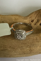 Front view of ring resting on wood to show top diamond cluster and pavé band.