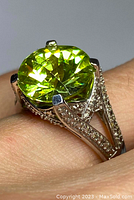 Close-up of the ring showing large green stone and diamond-set sterling silver split shank band.