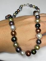 Necklace of multi-coloured pearls shown on hand, showcasing pearl variety and size