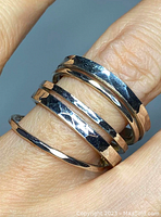 Close-up photo of the silver expandable hammered ring worn on a finger showing the overlapping bands and textured finish.