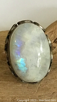 Close-up of the oval labradorite stone set in sterling silver bezel with iridescent blue and green flashes, showing surface details and natural inclusions
