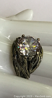Close-up image showing large clear round gem and textured silver modernist band with tarnish.