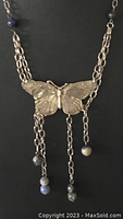 Close-up of sterling silver butterfly pendant with detailed wings and three chain dangles with sodalite beads at ends.