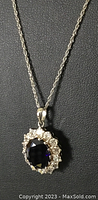 Close-up of the sterling silver necklace and synthetic sapphire pendant on a black background showing the details of the pendant and chain.