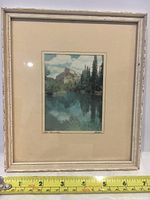 Full view of framed miniature artwork showing a mountain and water landscape with pine trees, in a distressed white frame with glass.