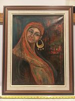 Framed thick oil painting on canvas of a woman wearing an orange textured headscarf and large gold earrings, with smiling expression in front of an abstract background.