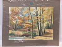 Original watercolor painting of an autumn landscape with trees, water, and fall colors, matted in brown and wrapped in plastic, front view