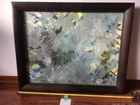 Front view of framed abstract oil painting showing dimensions with measuring tape.