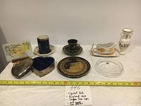 Photo showing all eight items including heart-shaped box, crystal dish, vase, cups, plaque, and other decorative pieces with ruler below for size reference