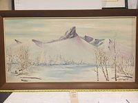 Front view of the framed oil painting depicting a winter mountain scene with snow and trees, showing overall condition and frame.