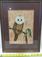 Framed batik artwork showing full view of owl sitting on branch with leafy detail, maroon mat and frame visible