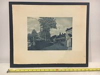 Wide view of framed black and white etching showing the overall artwork and frame with measuring tape for scale.