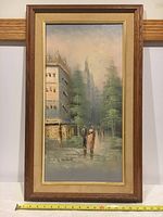 Full view of framed oil painting showing city street scene with two figures walking, misty background with tall buildings and trees, signed by artist A. Herbert.