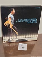 Front view of the box featuring Bruce Springsteen holding a guitar with stage lights background and text 'Bruce Springsteen & The E Street Band Live 1975-85'.