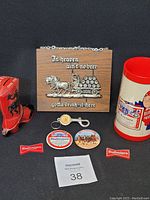 Photo of entire lot including beer mug, wooden wall plaque, pins, beer opener and fridge magnets arranged together