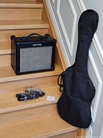 Black Kustom amplifier on stairs beside gig bag and cables