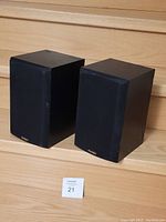 Front view of two black Paradigm Atom bookshelf speakers with fabric grills and Paradigm logos.