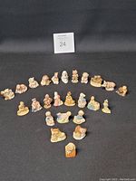 Full view of all 25 Wade ceramic figurines arranged on black cloth, showing variety of figures and animals