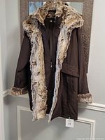 Full front view of the brown women's winter jacket with faux fur trim on hood, front, and cuffs. Showing double front closure.