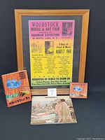 Framed Woodstock 1969 poster with three vinyl records, Woodstock 1994 book, and CD album.