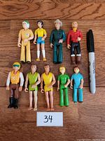 All 9 Fisher Price Adventure People figures laid out in two rows beside a marker for scale, showing various characters and clothing colors.