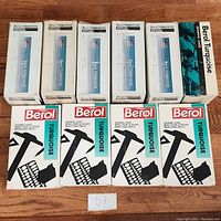 Top-down view of 10 Berol drawing lead boxes arranged in two rows. Five boxes in top row mostly white with turquoise text, five boxes in bottom row showing front of boxes with large black drawing lead graphics and turquoise Berol Turquoise label.