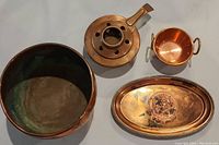 Photo of all four copper items including bowl, item with holes and handle, small cup, and hammered pot